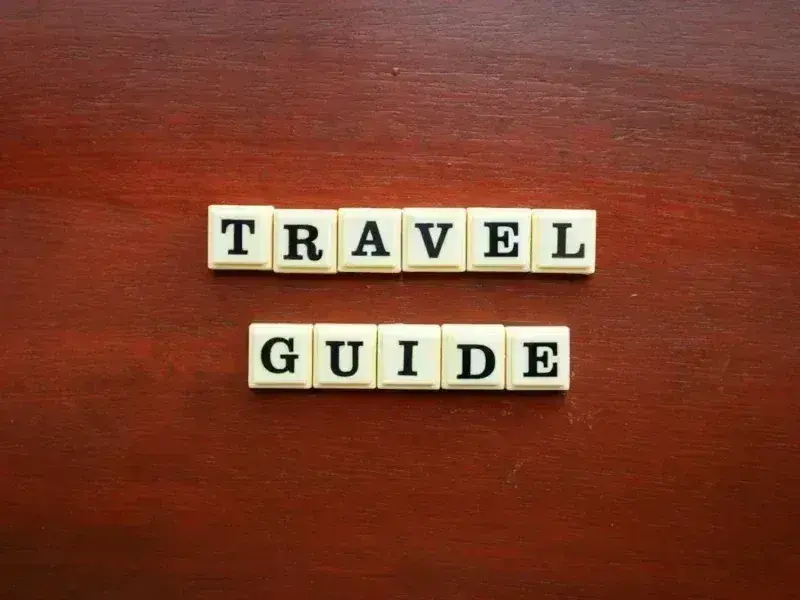 the word travel guide spelled with scrabble tiles